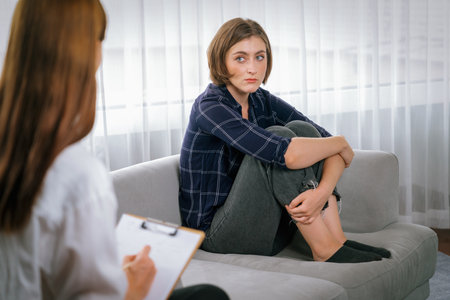 Sad PTSD woman patient in utmost therapy for mental health with psychologist, depression or grief after life failure. Frustrated trauma young woman talking to a psychologist about emotion in clinicの写真素材