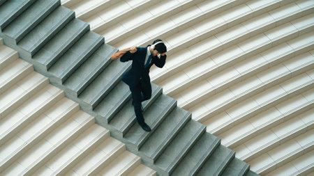 Happy business man listening to music from headphone while walking down at stairs. Executive manager dancing to celebrate increasing sales or successful project or getting new position. Exultant.の写真素材