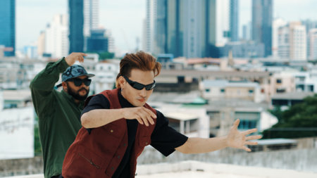 Motion shot of B-boy dance performance by professional street dancer at rooftop with sky scrapper,...