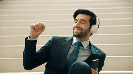 Closeup of smart business man listening and enjoy music while wear headphone. Project manager smiling while getting good news, getting promotion, increasing sales. Relaxing man enjoy music. Exultant.の写真素材