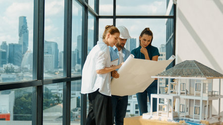 Professional architect engineer team talking, sharing, brainstorming about design while manager hold at project plan. Young architect holding plan while manager listen and point at plan. Traceryの写真素材