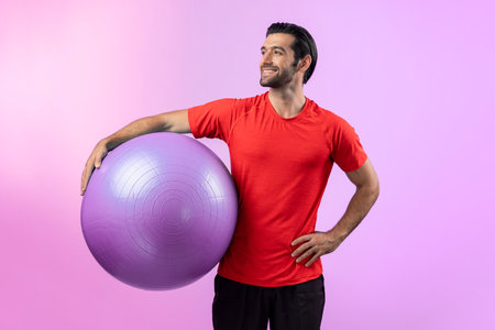 Full body length gaiety shot athletic and sporty young man with fitness exercising ball in standing posture on isolated background. Healthy active and body care lifestyle.の写真素材