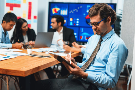 Portrait of businessman or analyst looking at camera with his colleague analyzing data analysis in dynamic business strategy investment planning meeting. Meticulousの写真素材