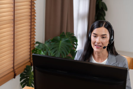 Female call center operator or customer service helpdesk staff working on workspace while talking on...