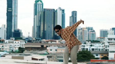 Hispanic break dancer practice B-boy footsteps at roof top with urban city view or sky scrapper. Young modern dancing group doing hip hop movement. Style,fashion,action. Outdoor sport 2024. Endeavor.の写真素材