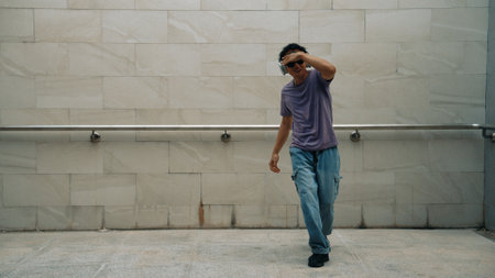 Motion shot of hipster listen music while move or dance to music at dancing room. Attractive street dancer practice b-boy footstep. Freestyle dance concept. Lifestyle. Outdoor sport 2024. Sprightly.の写真素材