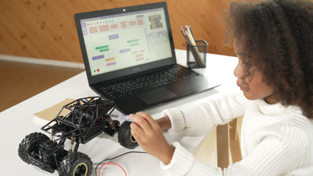 Smart african girl build robotic car while using wires while using laptop setting or writing prompt code. Skilled female student working on computer in STEM technology online classroom. Erudition.の写真素材