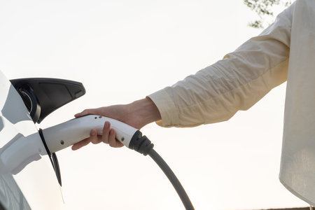 Young woman put EV charger to recharge electric cars battery from charging station. Alternative...