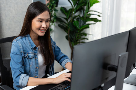 Working young beautiful asian creative manager typing keyboard to search on pc with website design on social media channel online planning with blue jeans shirt at modern home office. Stratagem.の写真素材