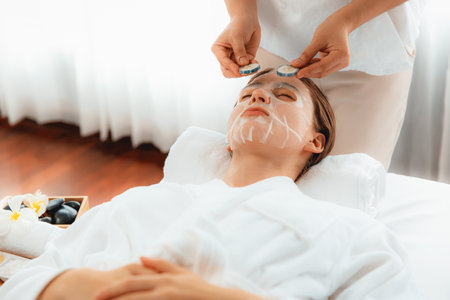 Serene daylight ambiance of spa salon, woman customer indulges in rejuvenating with luxurious cucumber facial mask. Facial skincare treatment and beauty care concept. Quiescentの写真素材