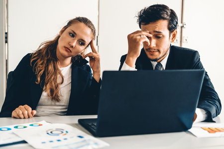 Unhappy serious businessman and businesswoman working using laptop computer on the office desk. Bad business crisis situation and bankruptcy concept. udsの写真素材
