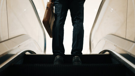 Cropped image of professional business man standing at escalators. Closeup of skilled project manager getting promotion, increasing skill, upgrading, getting new position. Center. Exultant.の写真素材