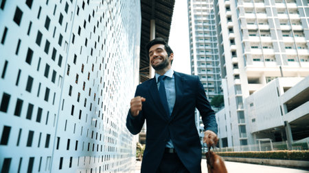 Skilled business man dancing with joyful while walking in city street. Project manger receive a good news, getting promotion, getting a successful job while express feeling of overjoy. Exultant.の写真素材
