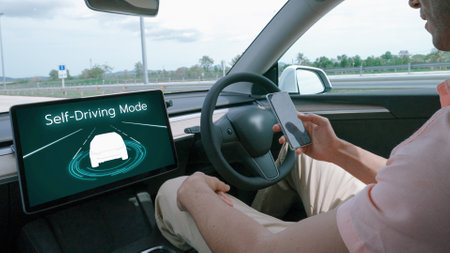 Self driving car or autonomous vehicle travel on speed highway with driverless system and autopilot mode allowing man driver relax and focus on smartphone without compromising safety. Perpetualの写真素材