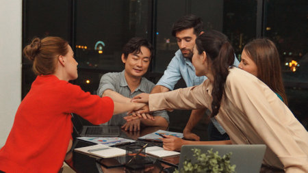 Businesspeople putting hands together and clapping hands to celebrate successful project at modern office with night city view. Group of manager with stacks of hands. Teamwork, trust. Traceryの写真素材