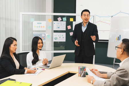 Successful businessmen present financial projects on glass whiteboard confidently. Executive managers listen to employees quarterly business plan presentation. Modern meeting room. Intellectual.の写真素材