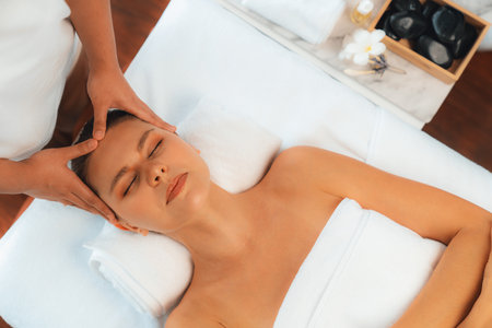 Panorama top view of woman enjoying relaxing anti-stress head massage and pampering facial beauty skin recreation leisure in dayspa modern light ambient at luxury resort or hotel spa salon. Quiescentの写真素材