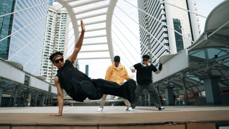 Group of professional street dancer cheer up while asian hipster perform freestyle footstep at city surrounded by people with low angle camera. Break dance concept. Outdoor sport 2024. Sprightly.の写真素材