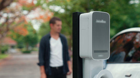 Man recharging battery for electric car during road trip travel EV car in autumanl season natural...