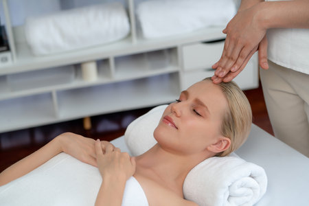 Caucasian woman enjoying relaxing anti-stress head massage and pampering facial beauty skin recreation leisure in dayspa modern light ambient at luxury resort or hotel spa salon. Quiescentの写真素材