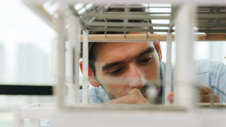 Closeup of young caucasian skilled architect engineer focusing on checking the house model structure with confident. Male worker looking at house construction. Creative design concept. Traceryの写真素材