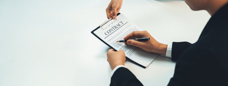 Business executive signing contract agreement document on the bale with the help from company attorney or lawyer service in law firm office. Business investing and finalizing legal processing. Shrewdの写真素材