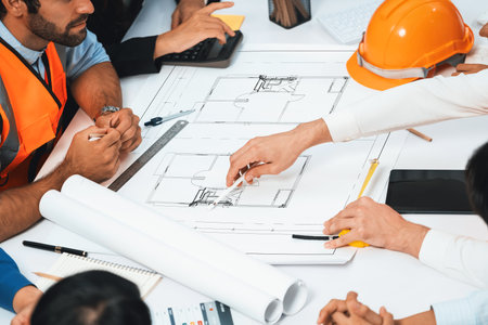 Diverse group of civil engineer and client working together on architectural project, reviewing construction plan and building blueprint at meeting table. Prudentの写真素材