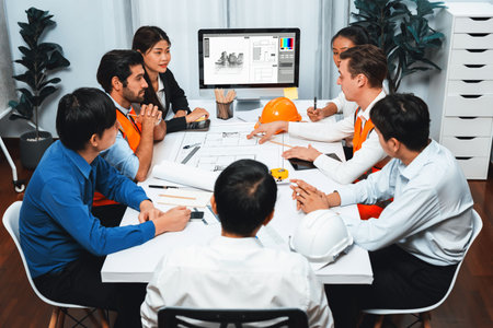 Diverse group of civil engineer and client working together on architectural project, reviewing construction plan and building blueprint at meeting table. Prudentの写真素材