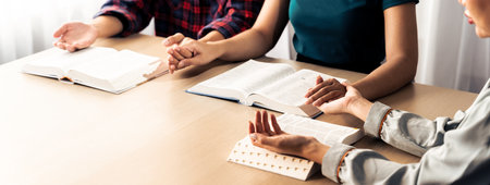 Cropped image of diversity people hand praying together at wooden church on bible book. Group of...