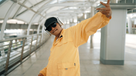 Closeup of skilled hipster listen music from headphone while moving hand. Professional break dancer perform freestyle footstep while walking and looking at camera. Outdoor sport 2024. Sprightly.の写真素材