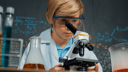 Smart boy using microscope analysis sample at science laboratory in STEM science class or chemistry lesson. Happy caucasian student looking under scope to inspect chemical liquid in tubes. Erudition.の写真素材