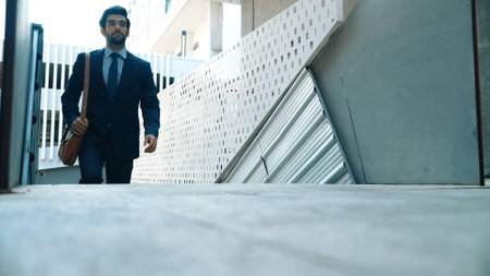 Smart business man walking up the stairs with confident near building. Skilled project manger...