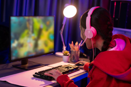 Host channel of young beautiful Asian gaming streamer playing fighting Moba at battle arena game on pc screen with multiplays, wearing pastel headphone at neon digital light modern room. Stratagem.の写真素材