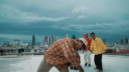 Professional asian street dancer practice B boy dance while multicultural friends at roof top. Young modern dancing group doing hip hop movement. Style,fashion,action. Outdoor sport 2024. Endeavor.の写真素材