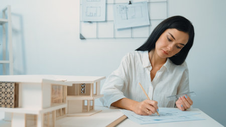 Closeup image of young architect engineer writing house structure in blueprint with document and...
