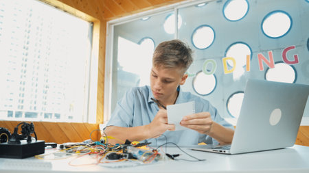 Smart happy boy inspect or learning to use electronic tool while taking a note. Happy highschool...