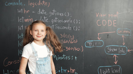 Happy caucasian girl looking at camera while standing at board with engineering prompt or coding, programing system written in STEM technology classroom. Pretty student smile at camera. Erudition.の写真素材