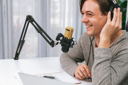 Host channel in smiling smart broadcaster recording, talking show with script and smartphone on desk...