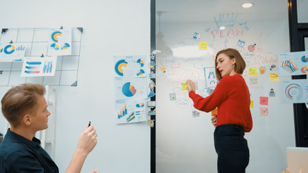 Young beautiful caucasian businesswoman presenting marketing strategy by using mind map, graph while answering questions with confident. Teamwork, brainstorming, discussing concept. Immaculate.の写真素材