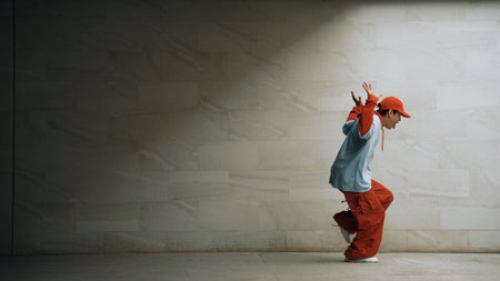 Handsome choreographer practice street dance in gray background. Young attractive b boy dancer perform while wearing stylish cloth. Feeling of lively step. Copy space. Outdoor sport 2024. Sprightly.の写真素材