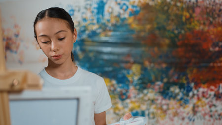 Multicultural student paint the canvas together in art lesson with colorful stained wall. Closeup of african boy and caucasian girl drawing picture or doing creative activity together. Edification.の写真素材