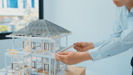 Closeup image of professional male asian architect engineer hand focusing on measure modern house model at white modern office. Focus on hand. Creative living and design concept. Immaculate.の写真素材