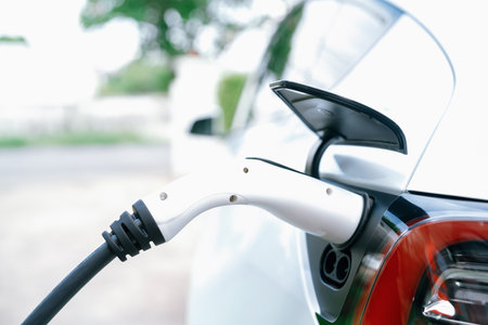 Closeup EV charger plug handle attached to electric vehicle port, recharging battery from charging station. Modern designed EV car and clean energy sustainability for better future concept. Synchronosの写真素材