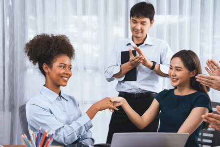 Diverse coworkers celebrate success with handshake and teamwork in corporate workplace. Multicultural team of happy professionals united in solidarity by handshaking in office. Concordの写真素材