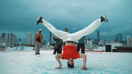Hispanic hipster dancing surrounded by multicultural friend at city view with blue sky. Group of street dancer performing at rooftop. Active, fun, happy atmosphere. Outdoor sport 2024. Endeavor.の写真素材