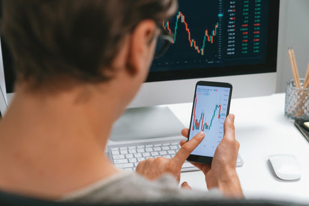 Smart stock investors pointing on screen with smartphone for market stock exchange along with laptop screen in highest dynamic investment rate, focusing data planning at modern workplace. Pecuniary.の写真素材