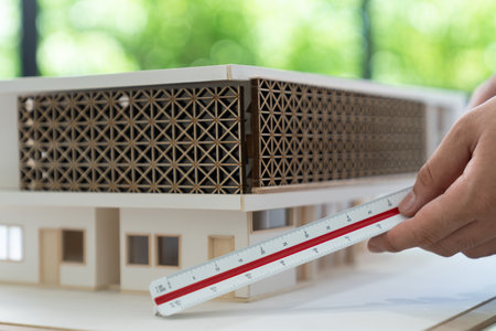 Closeup of professional architect hand measuring house model by using ruler and architectural equipment at modern office. Creative business design concept. Focus on hand. Immaculate.の写真素材