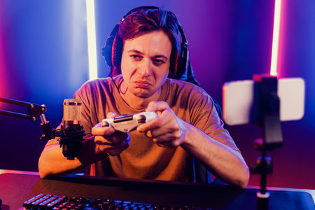 Enjoy smart gaming streamer with control joystick, playing game online of live streaming by smartphone rec with team skilled players on computer at modern technology cyber neon light room. Pecuniary.の写真素材