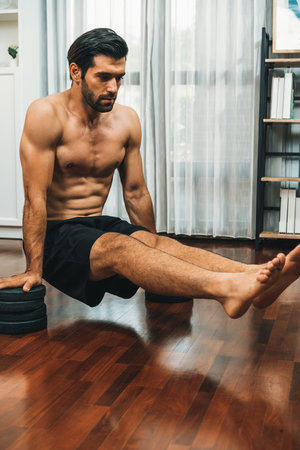 Athletic body and active sporty man lifting himself for effective targeting muscle bodybuilding gain at gaiety home as concept of healthy fit body home workout. Bodybuilder at home gym lifestyle.の写真素材