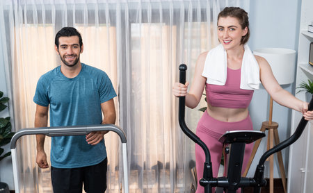 Athletic and sporty young couple or fitness buddy running on running machine together, home body...